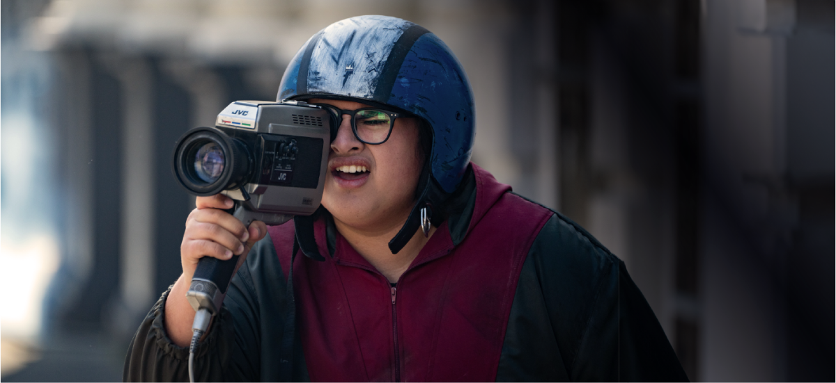 Still from Uproar showing a man in a helmet looking through a video camera