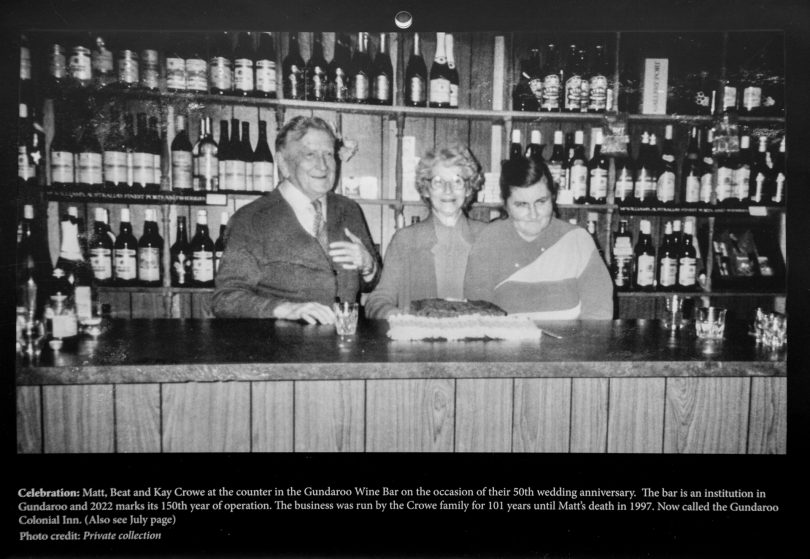 Black and white photo of three people behind a bar 
