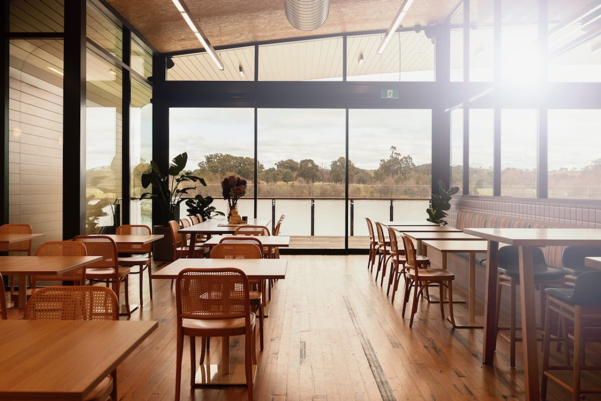 Interior of cafe with sunlight streaming through large windows.