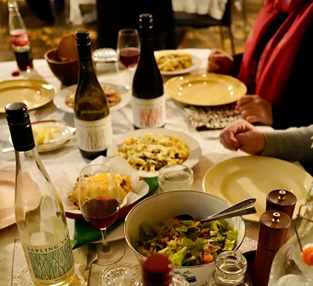 Table with many dishes of food and bottles of sapling yard wines.