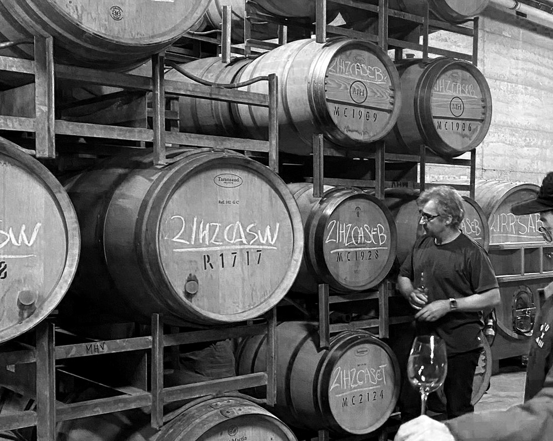 Black and white photo of barrel room with winemaker. 