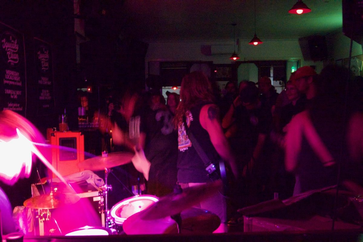 Interior of bar with pink lights and band performing.