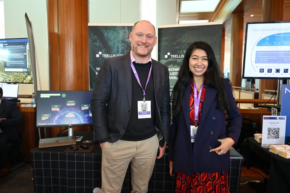 Two people standing in an office in front of AI computers.