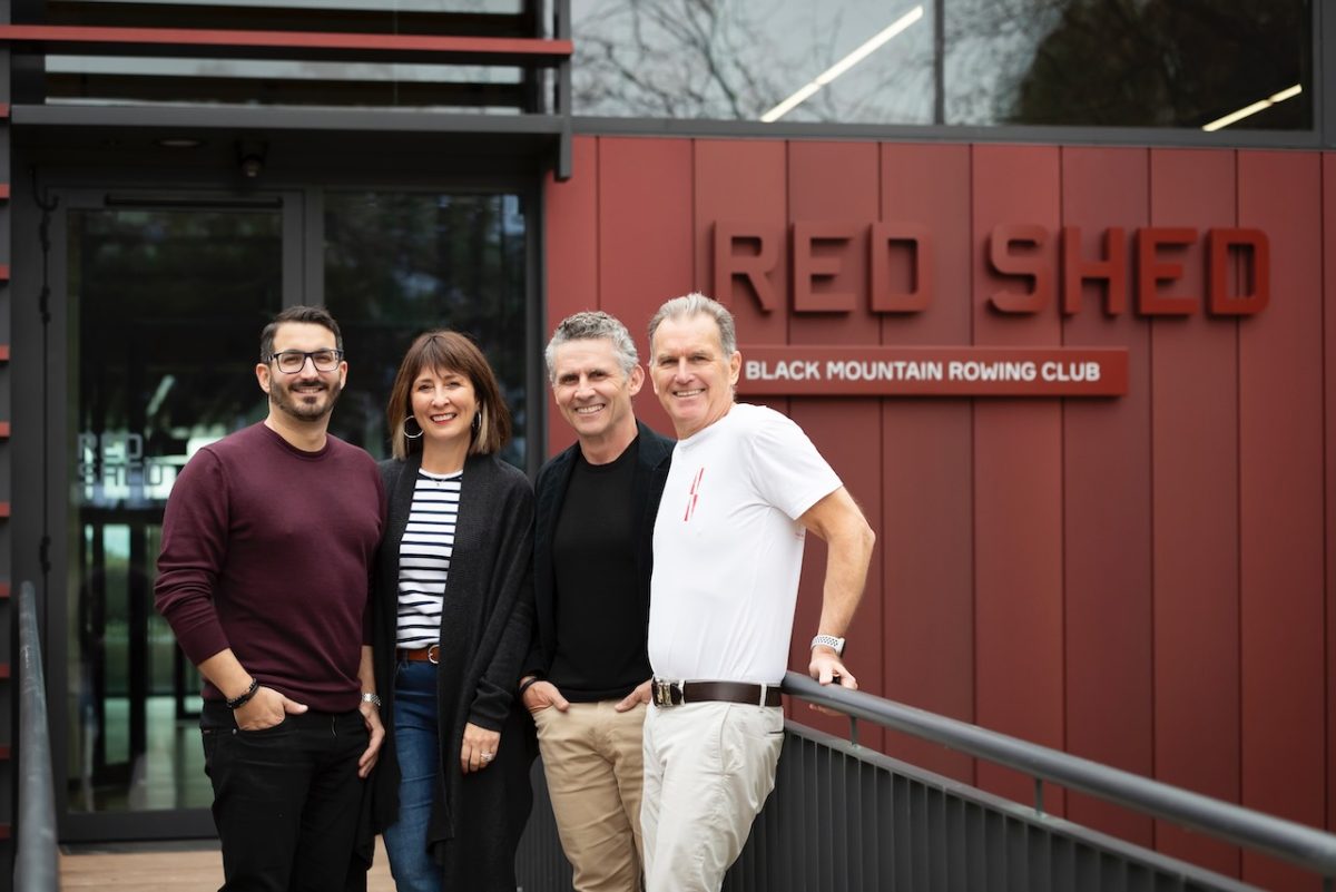 Four people outside the Red Shed