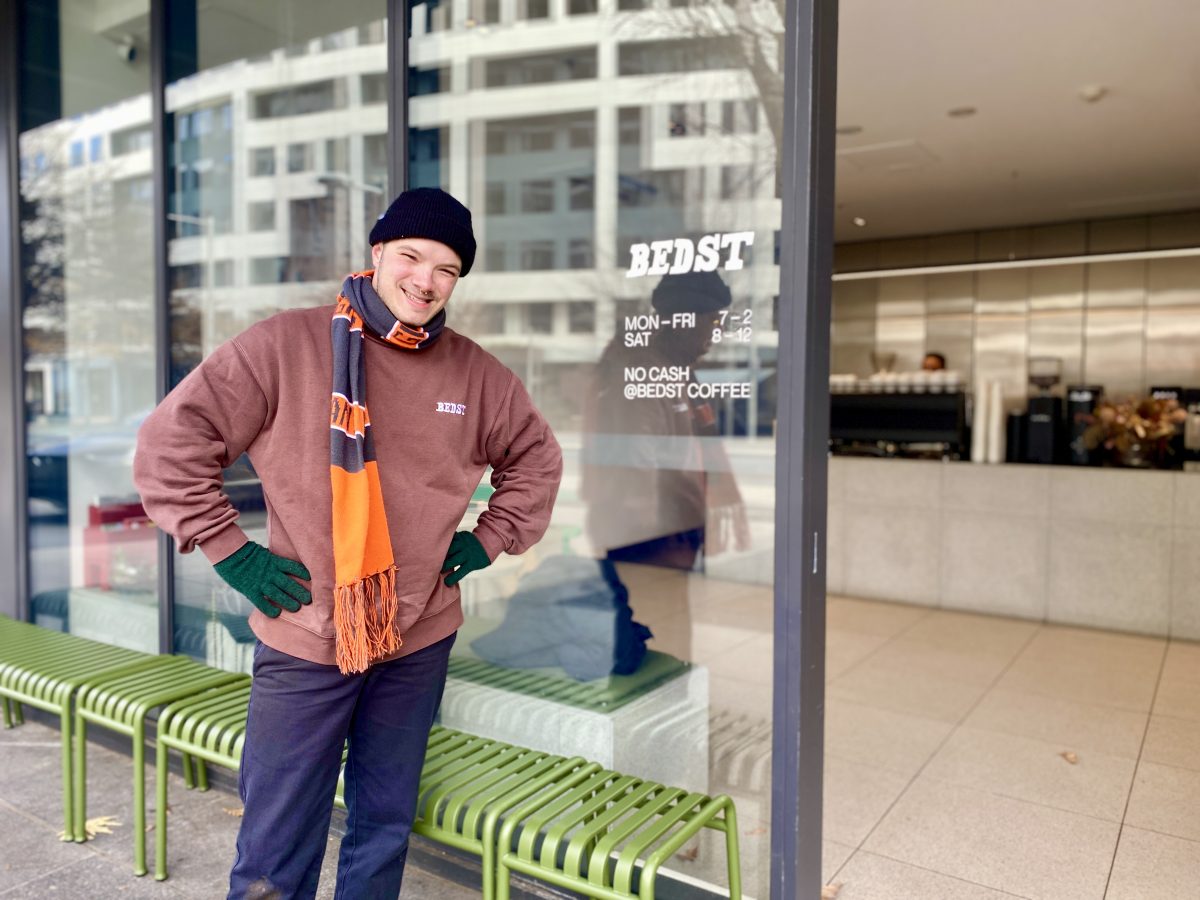 James Perry wears gloves, striped scarf and beanie outside Bedst Coffee shop.