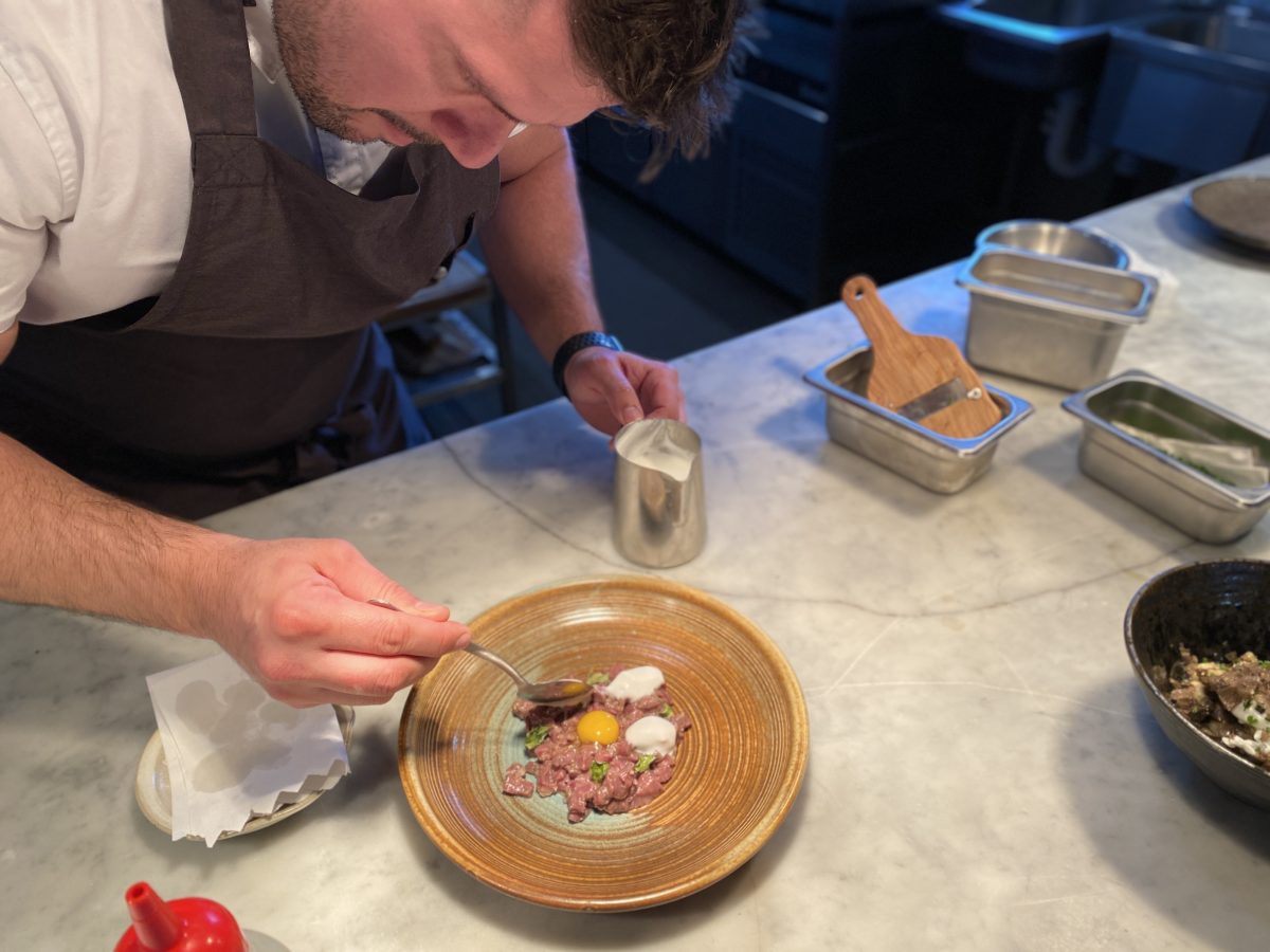 Chef spoons a foam onto a dish.