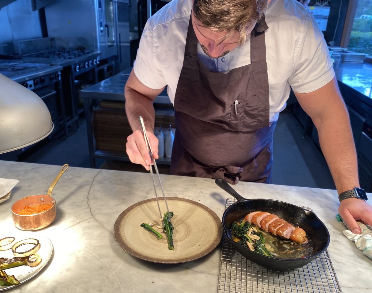 Chef uses tweezers to plate up a dish. 