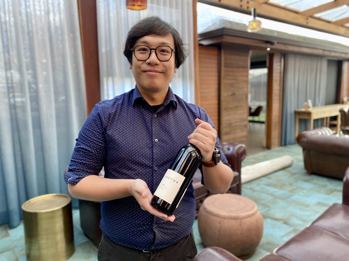 Man with glasses holds a bottle of wine.