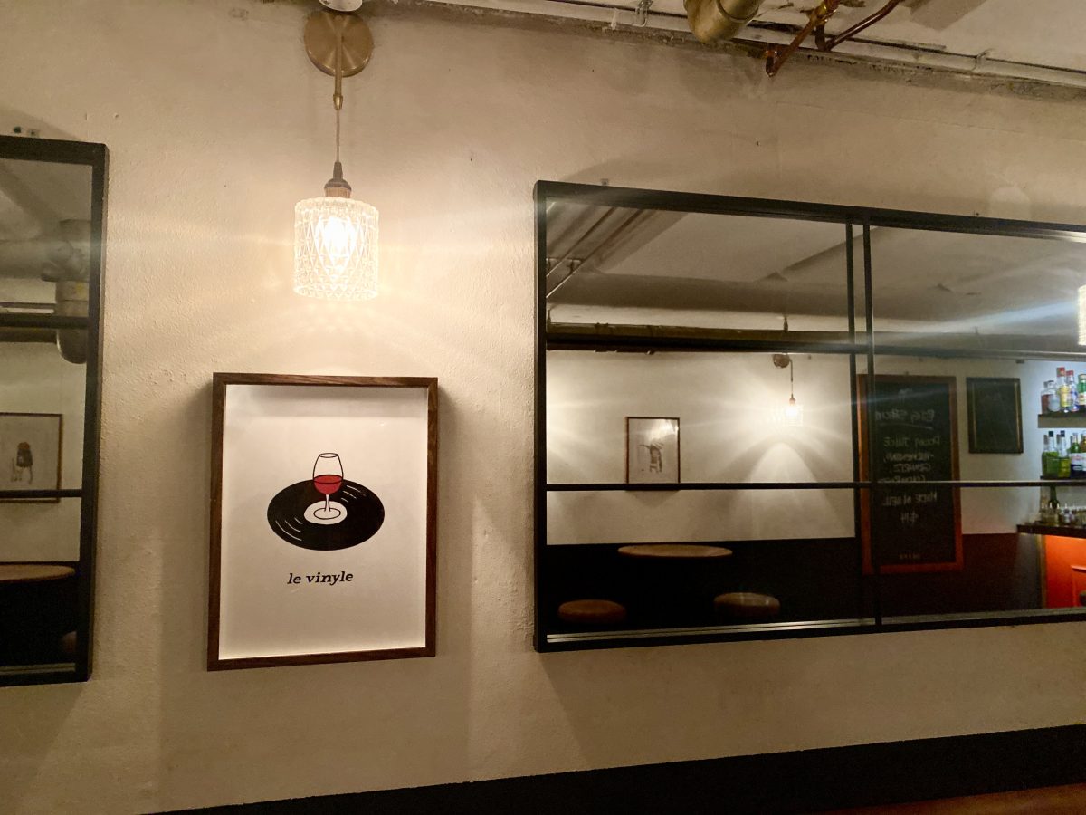 Print on a wall with mirrors featuring a wine glass on vinyl record.