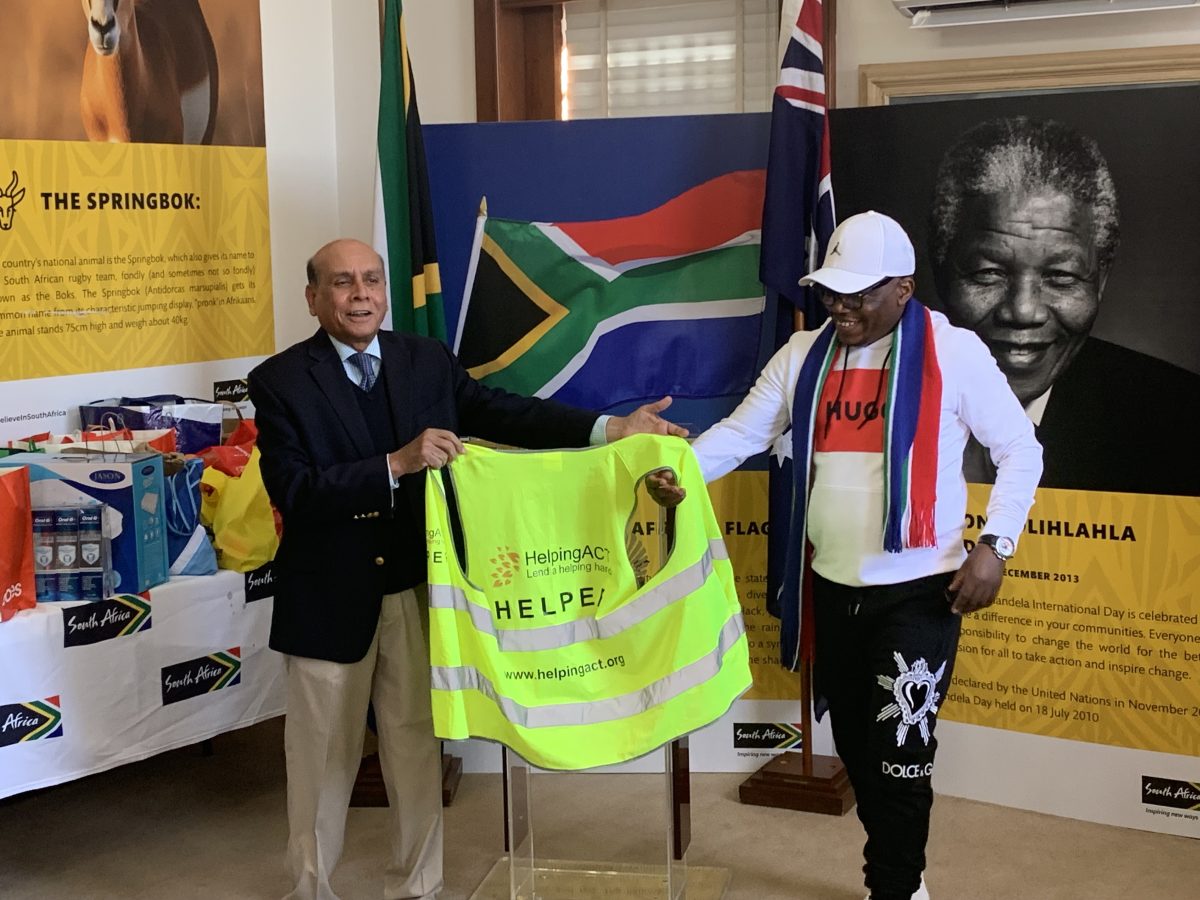 South African Acting High Commissioner Leonard Khoza and Helping ACT Board Chair Mohammed Ali holding a HelpingACT high-vis jacket together.