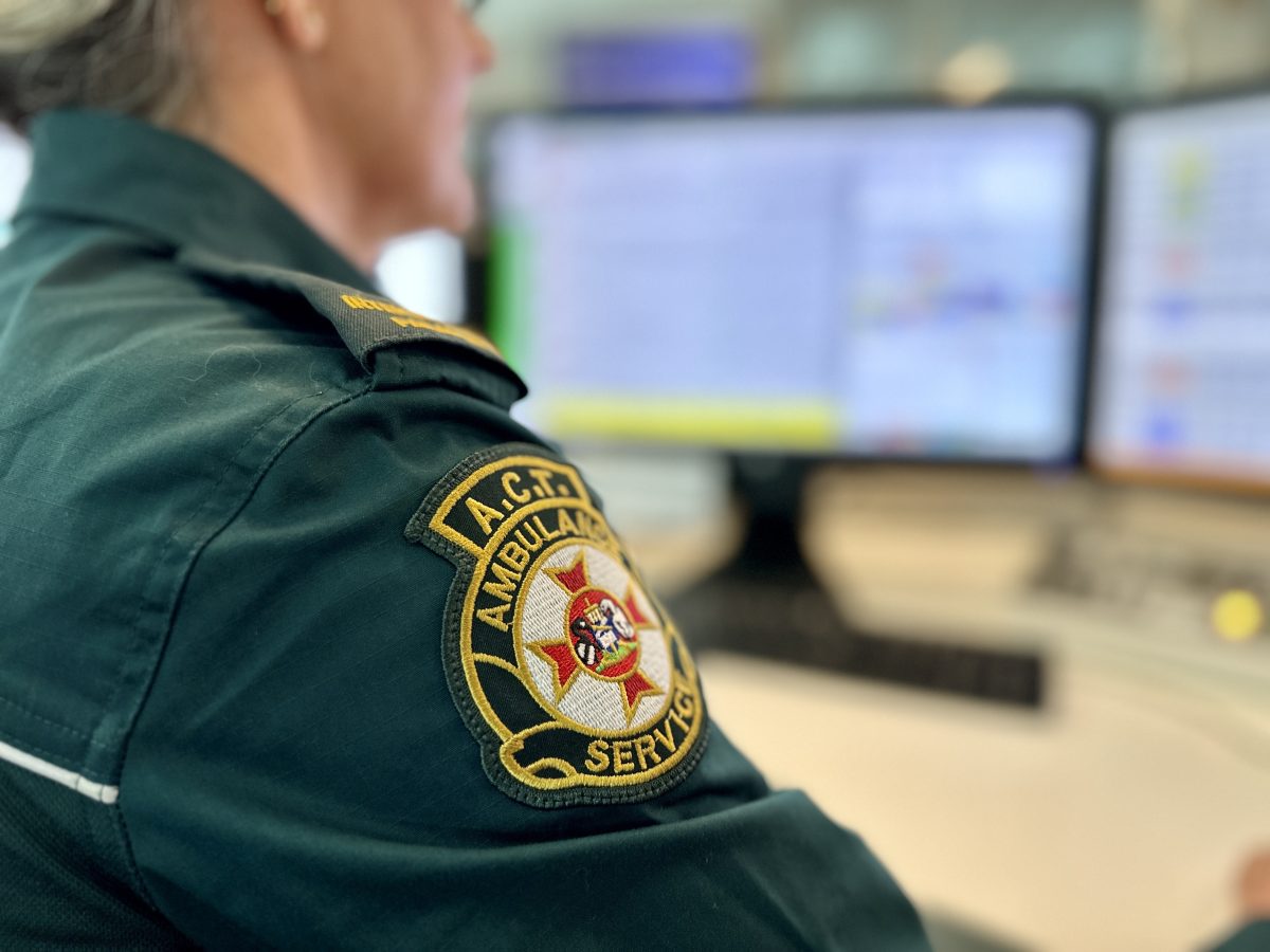 badge on uniform of paramedic sitting at her desk