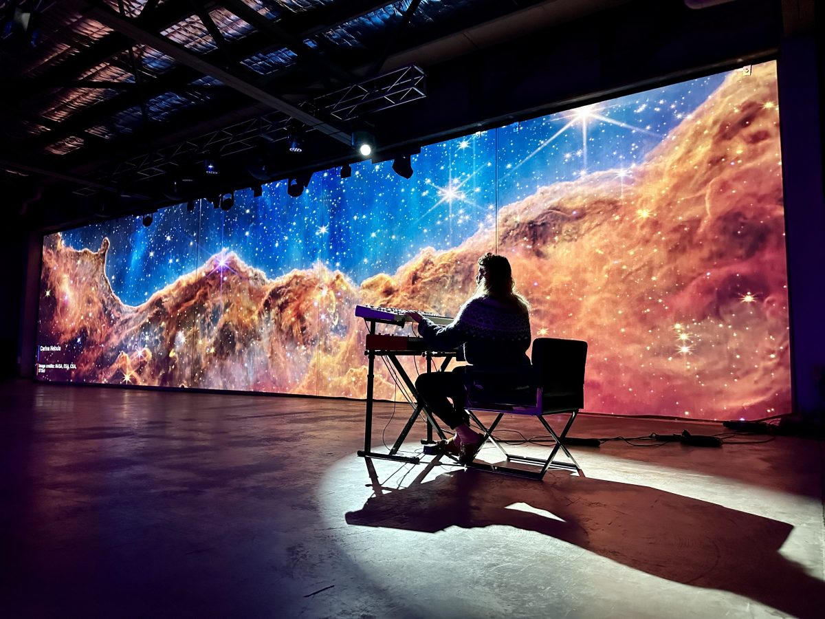 An image of space projected onto a wall and a person on a panel