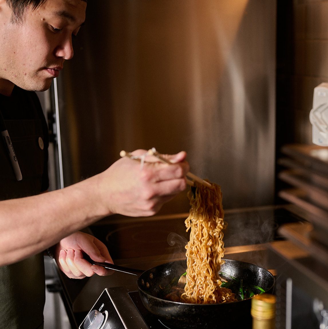 Mork pulls noodles from pan.