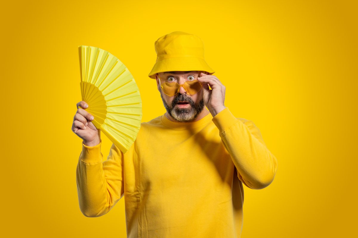 Man wearing a yellow hat holding a yellow hand-fan