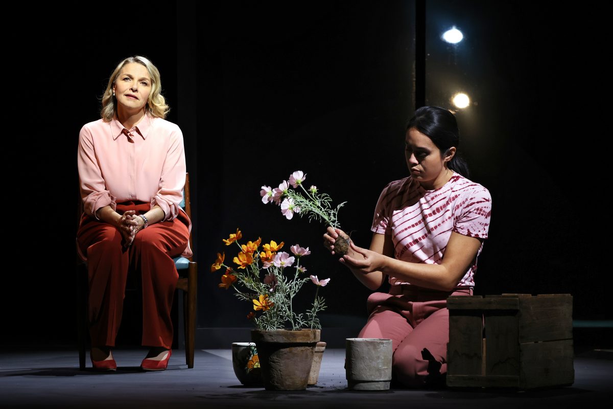 Two women on stage, one arranging flowers