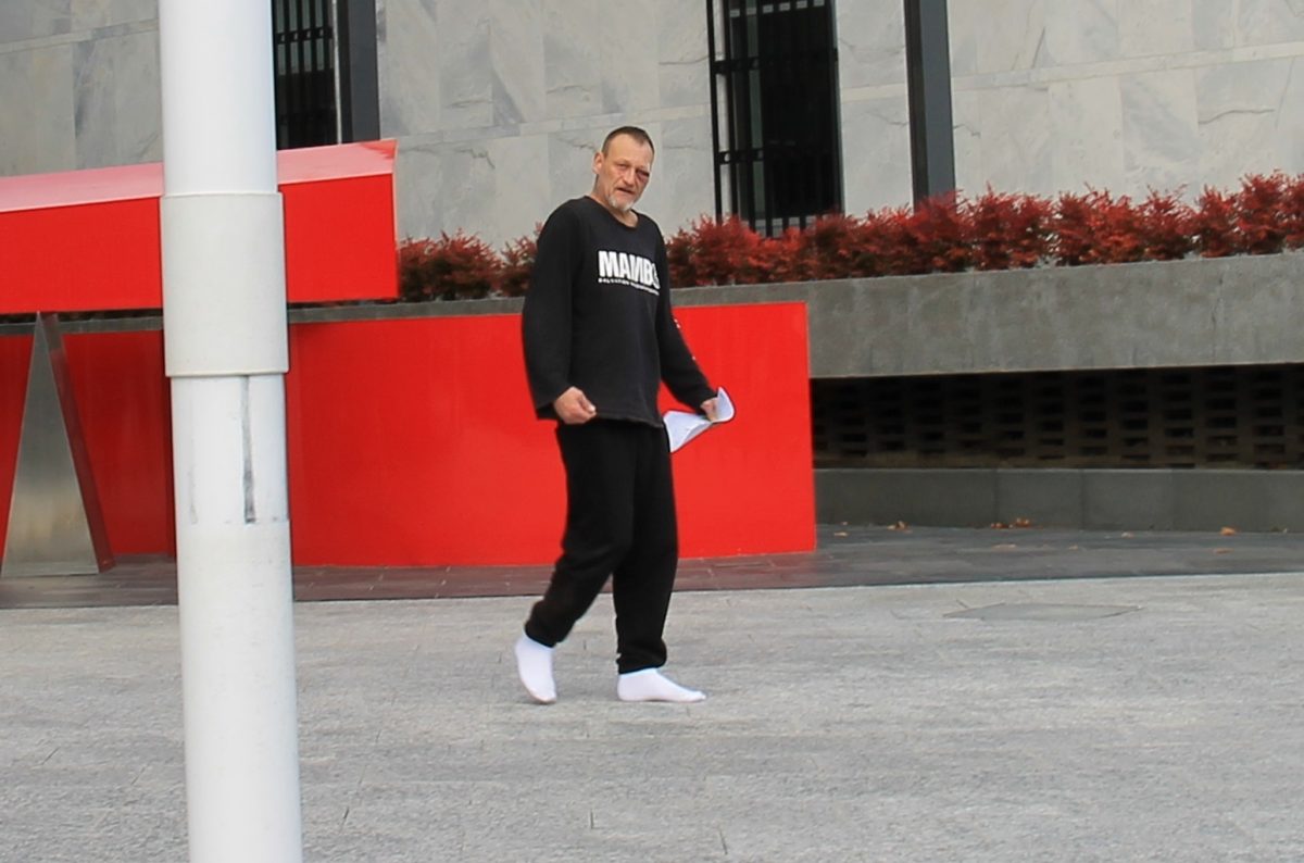 A man in black clothes and white ankle socks walking outside