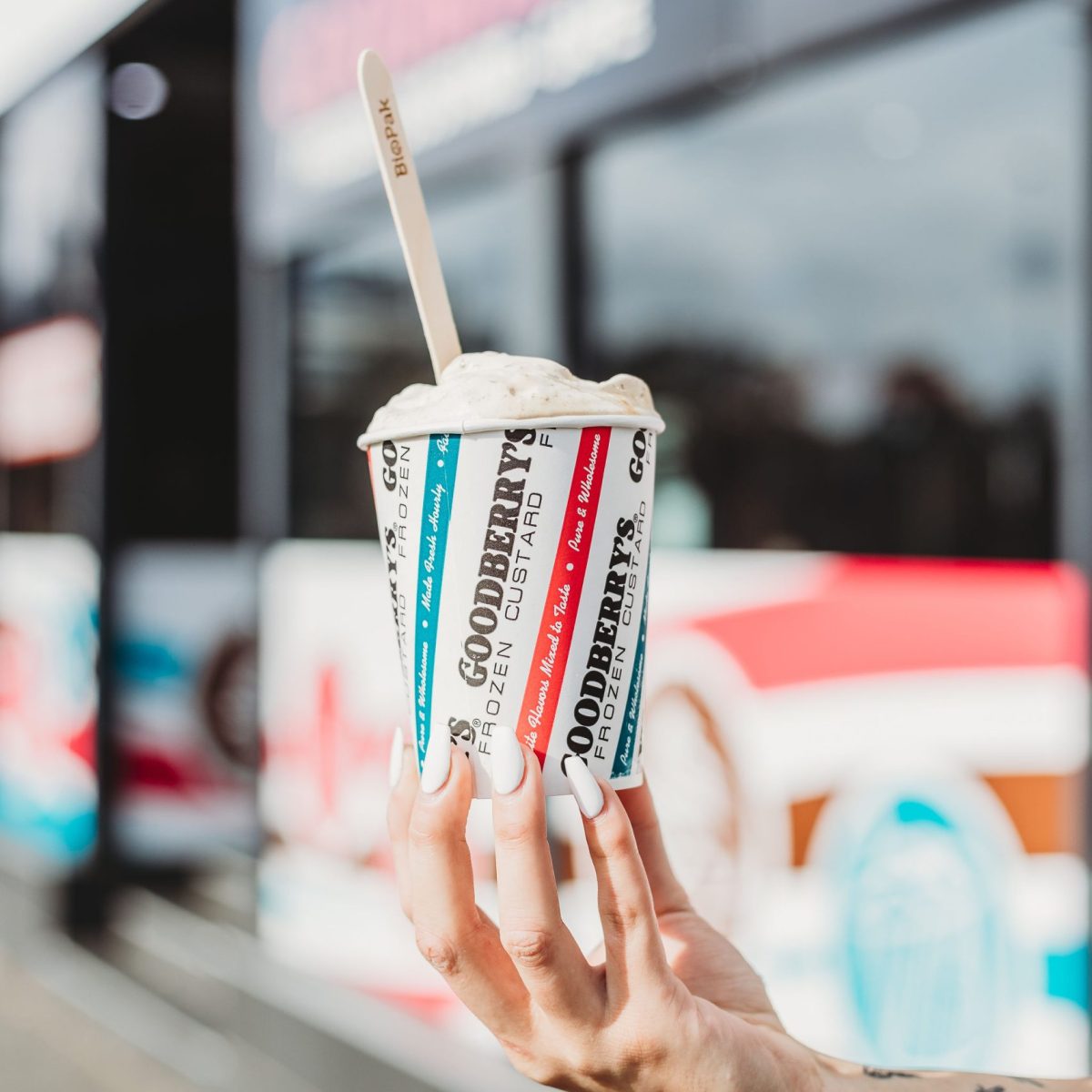 Hand holds a Goodberry's branded cup filled with frozen custard.