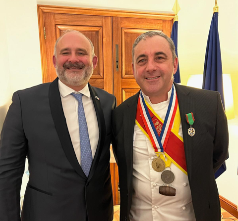 two men, one with medals around his neck