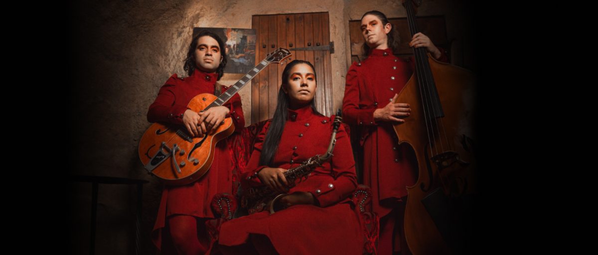 Three musicians in red robes pose with their instruments
