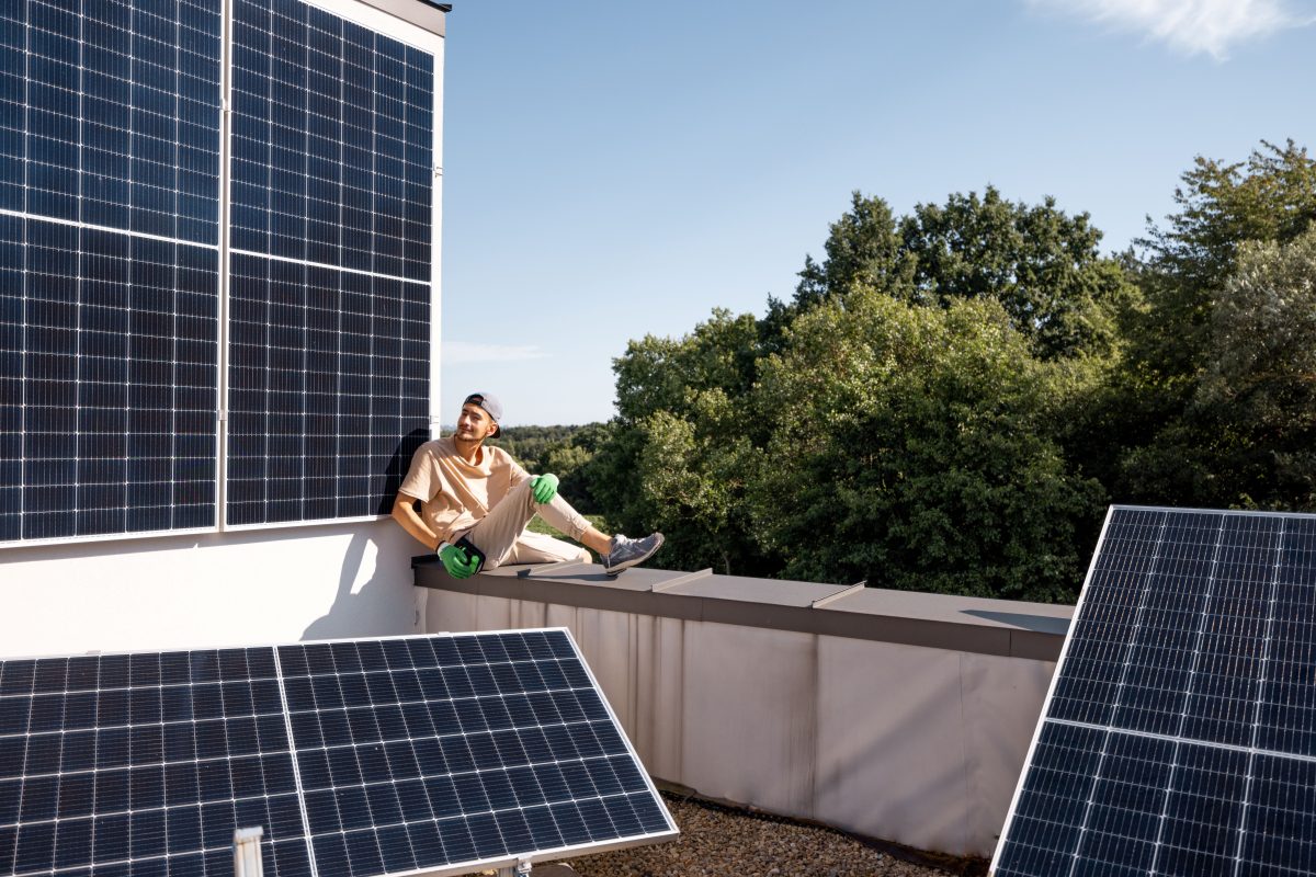 man sitting next to rooftop solar system