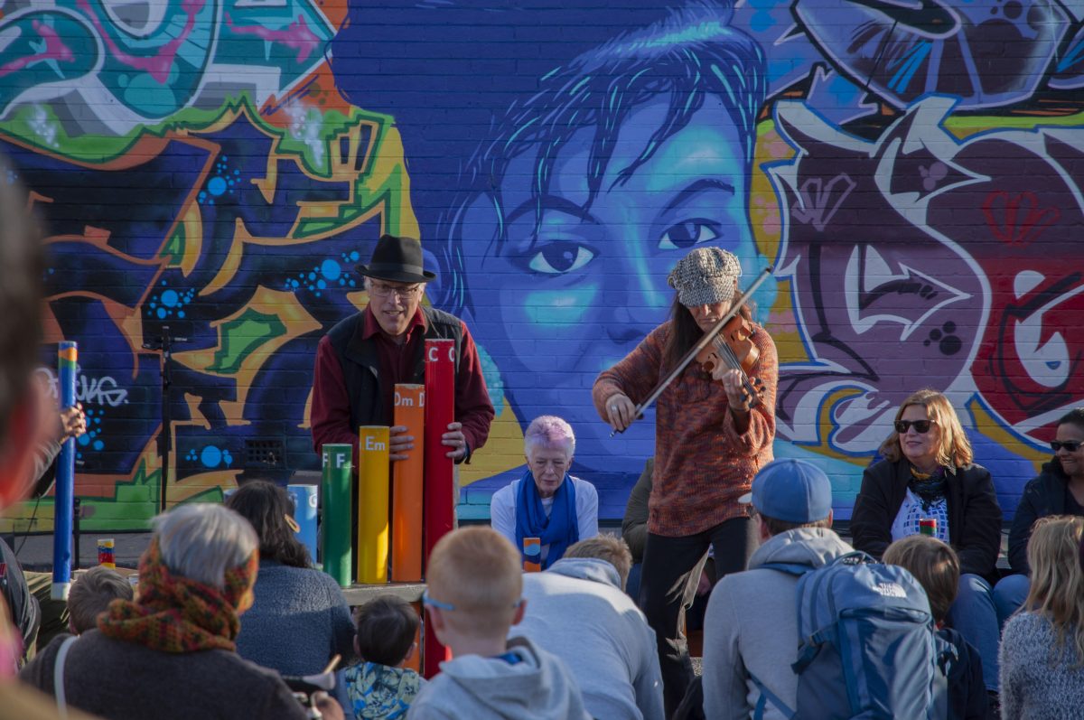 Musicians play in front of mural