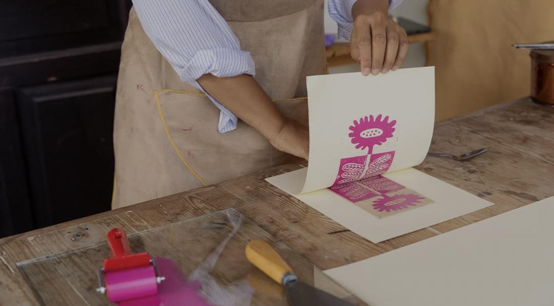 A person making a pink print on a piece of paper