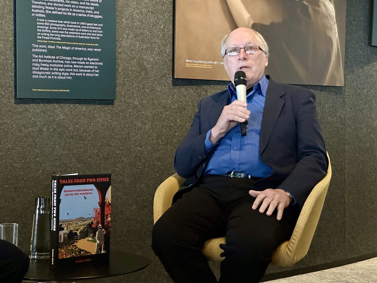 man sitting with a microphone next to books