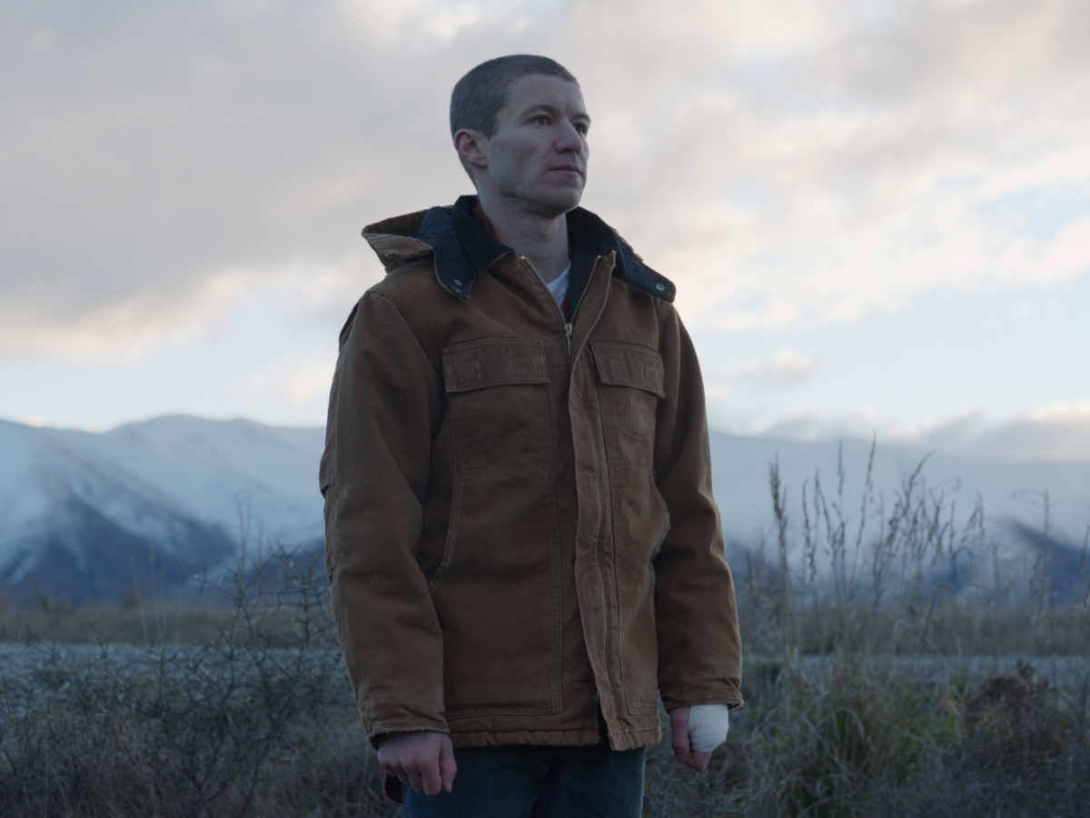 Still from the film Stray showing a man looking away from the camera in a cold landscape