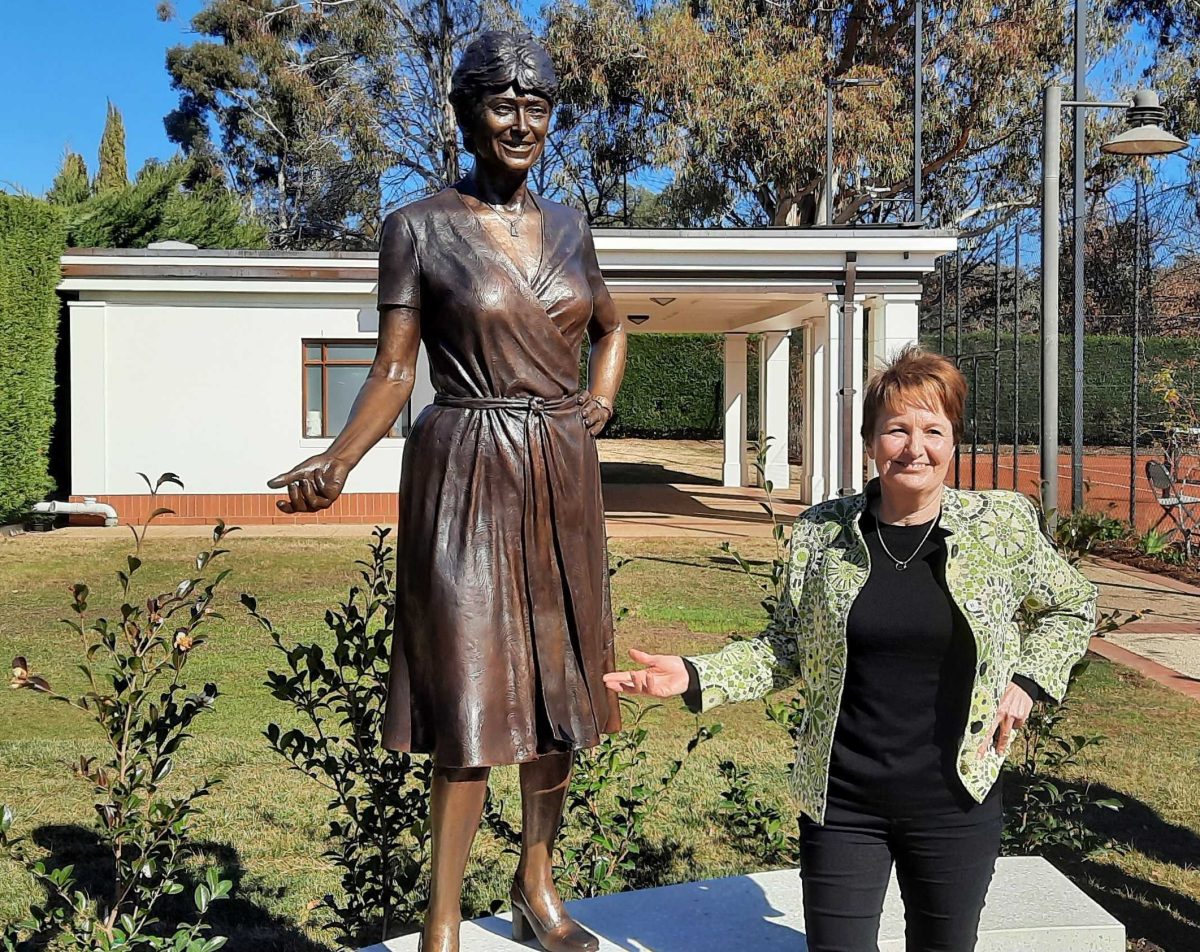 woman standing next to a statue