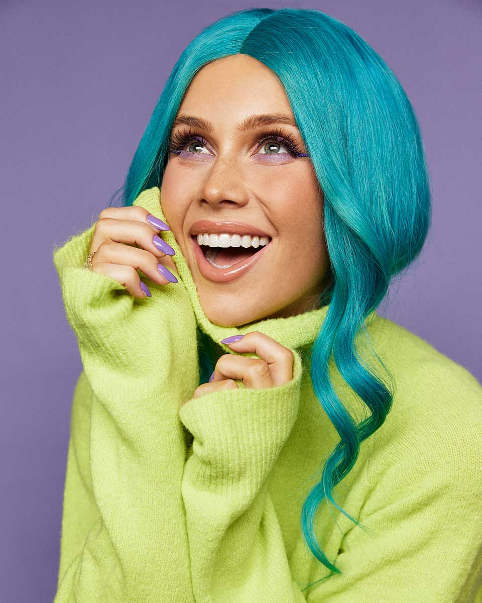 A smiling woman with blue hair and a green jumper