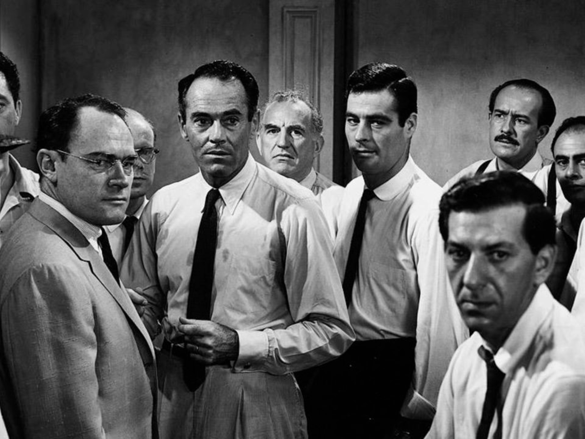 Black and white still from 12 Angry Men showing a room of men