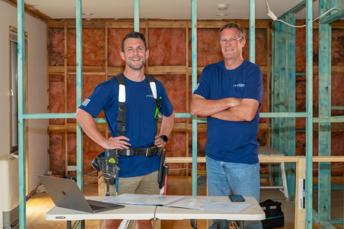 two people wearing blue t-shirts and tools standing in a house being renovated