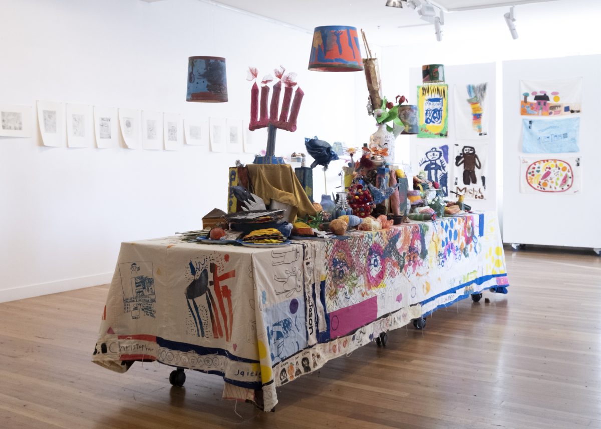 A laden table with an elaborate painted table cloth seen from an angle