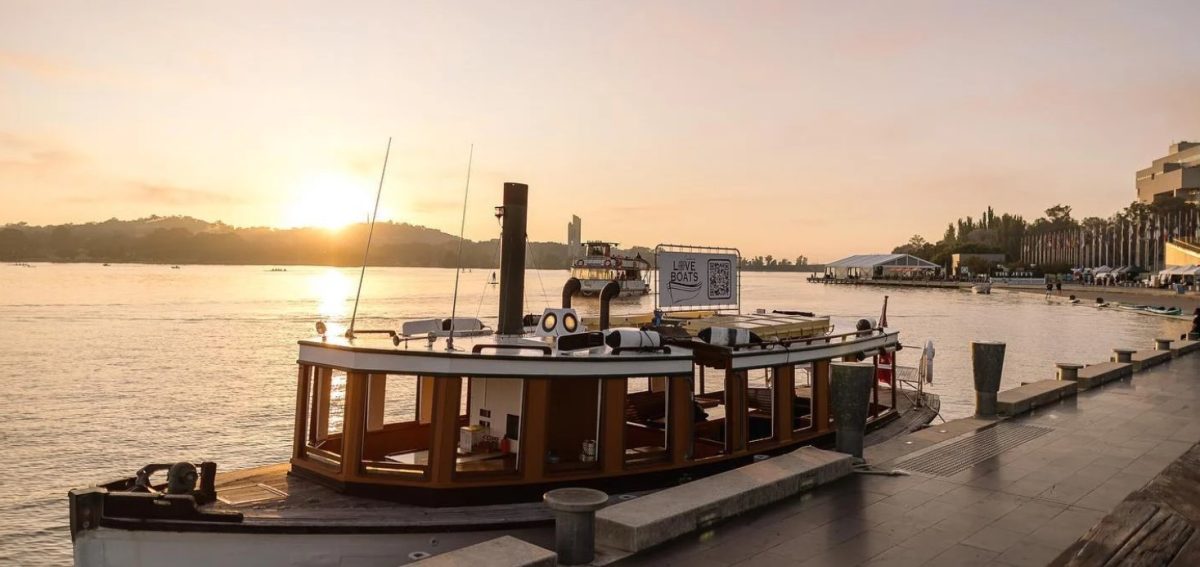 An old-fashioned wooden boat on the lake at sunset.