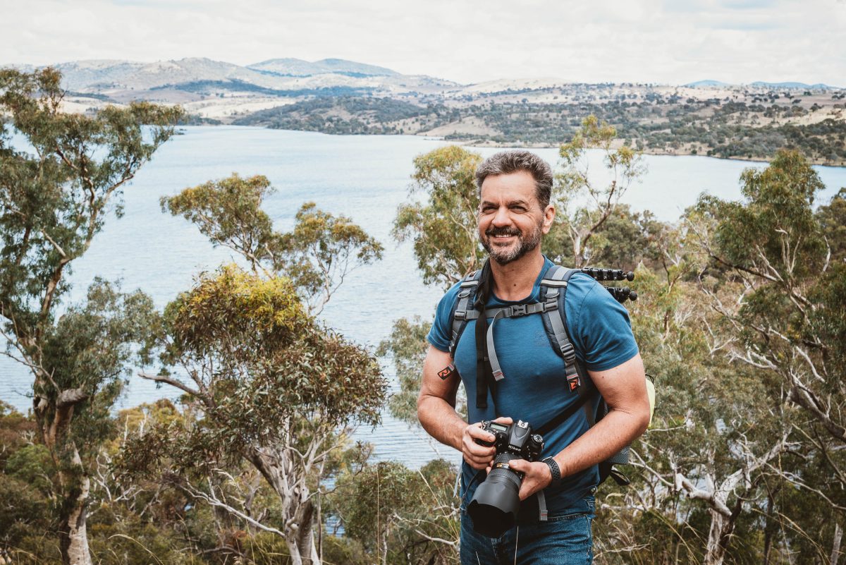 Man with camera standing above dam full of water