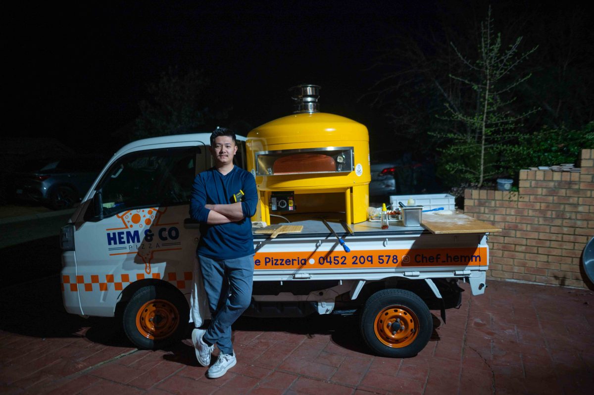 A man stands next to a truck with a pizza oven on the ute tray.