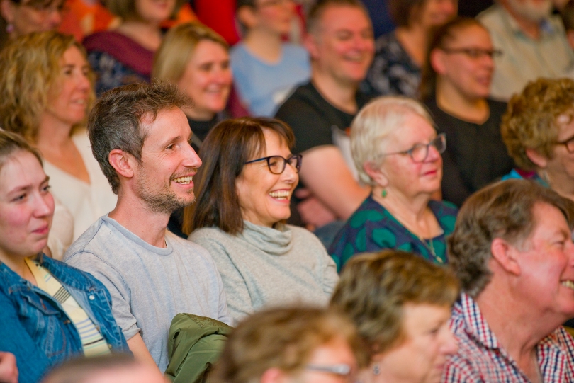 An audience sitting in a crowd with smiling faces.