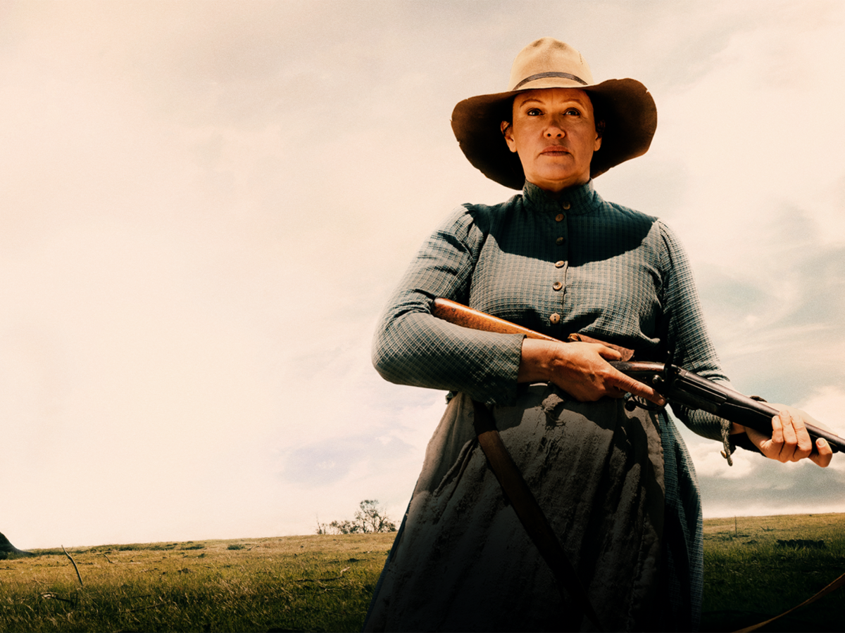 Still from The Drover's Wife The Legend of Molly Johnson showing a woman holding a rifle in a sparse landscape