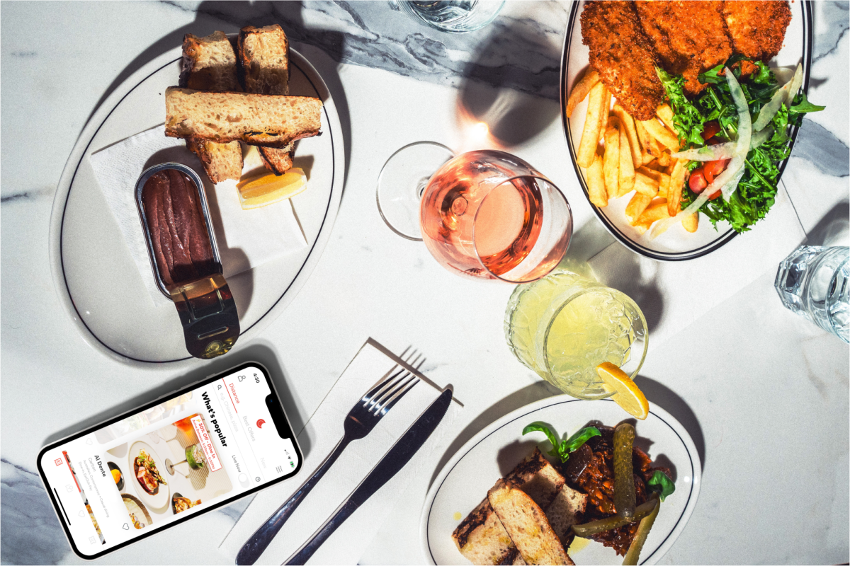 a table of food and drinks with a phone showing the EatClub app