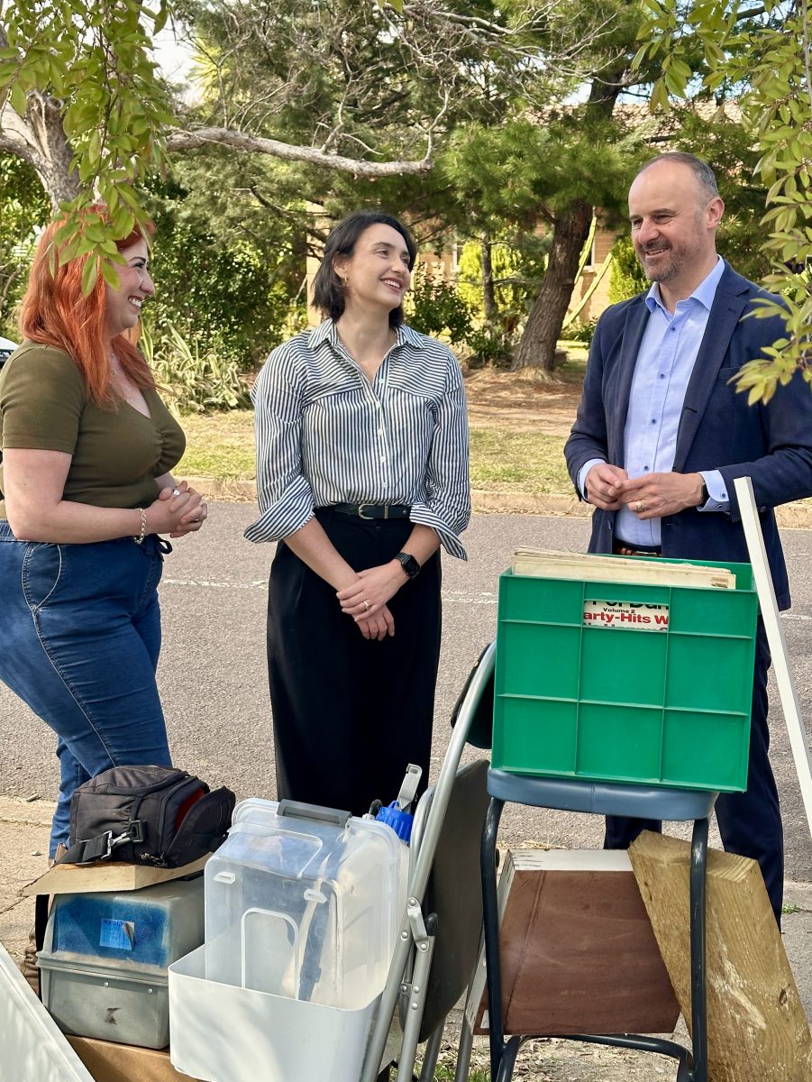 three people standing around kerbside rubbish