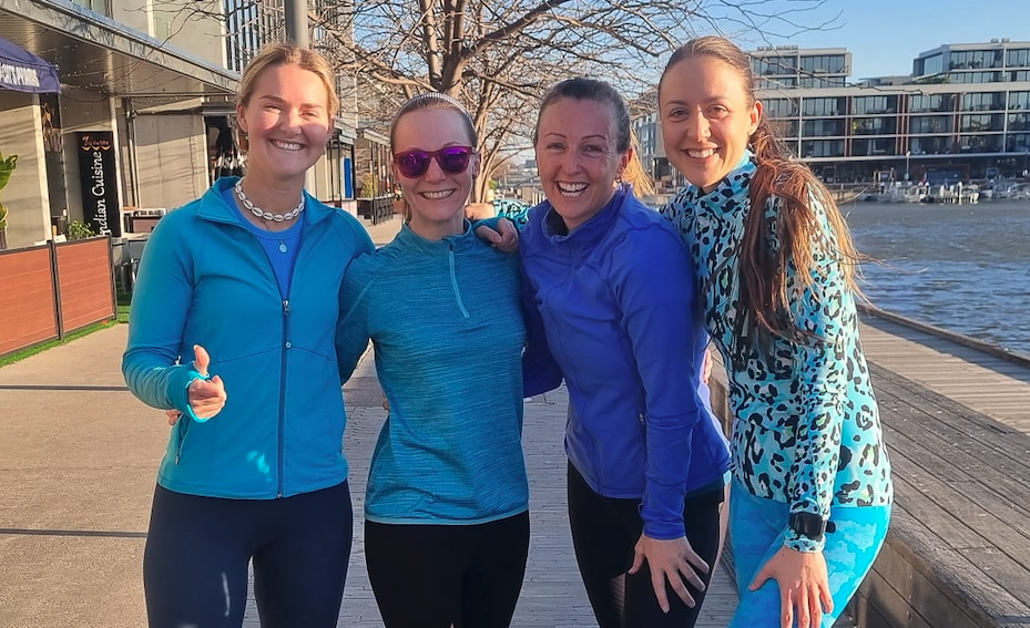 Four women in blue jackets smiling at the camera