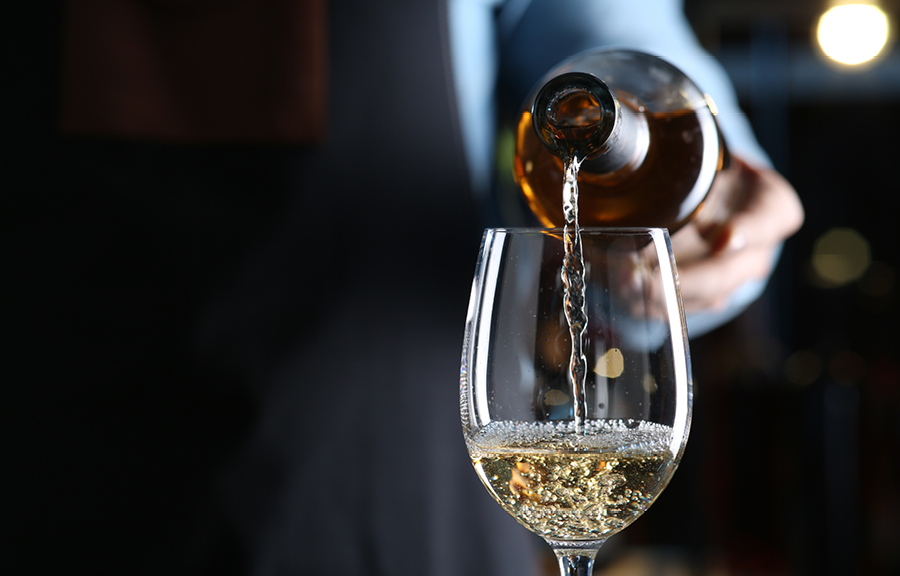 A person pouring white wine into a wine glass