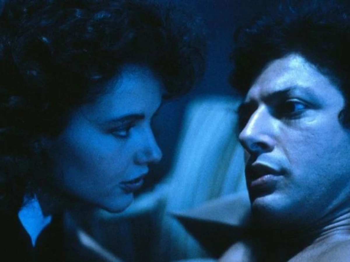 Still from The Fly showing a close-up of a man and a woman's faces in blue light