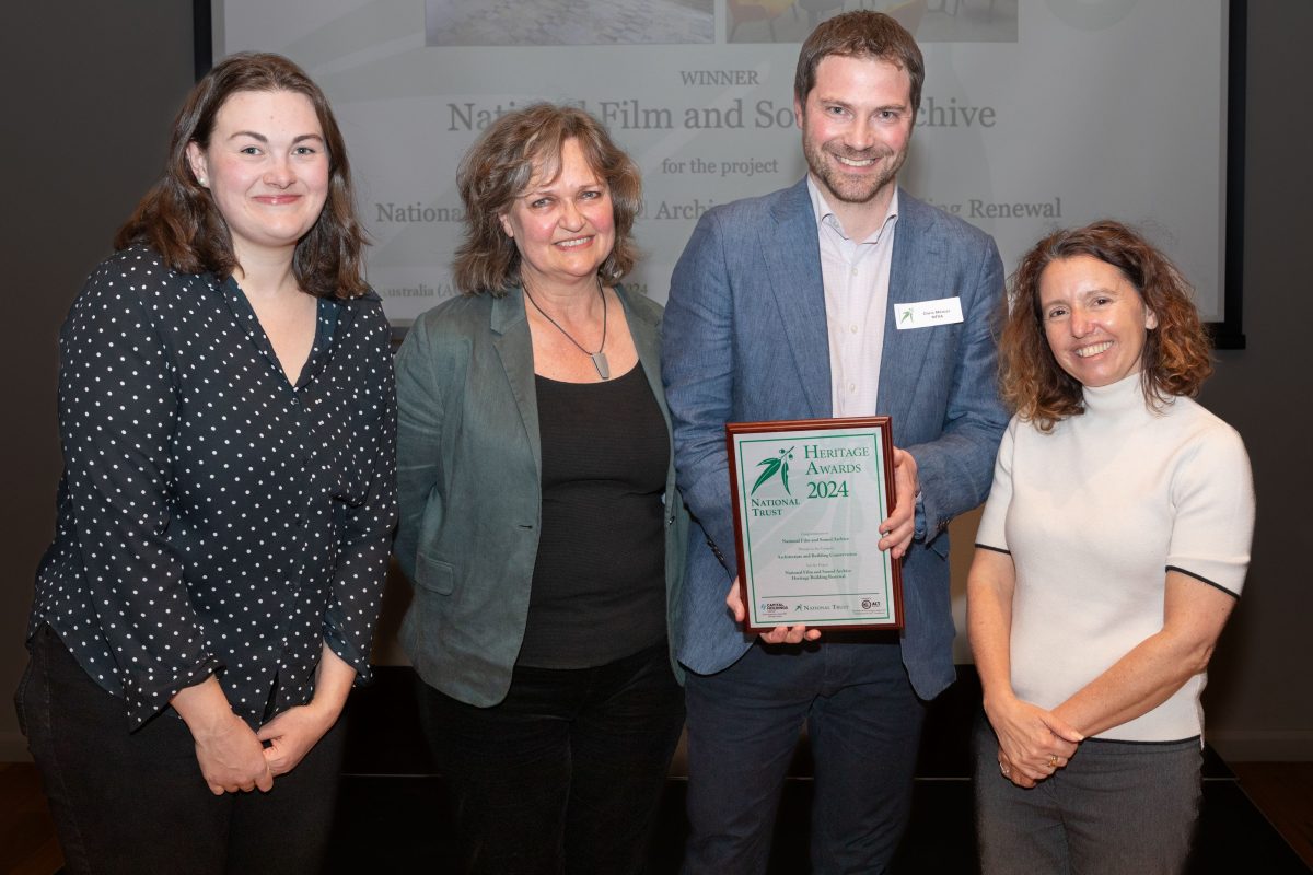 Three women and a man holding a framed certificate.