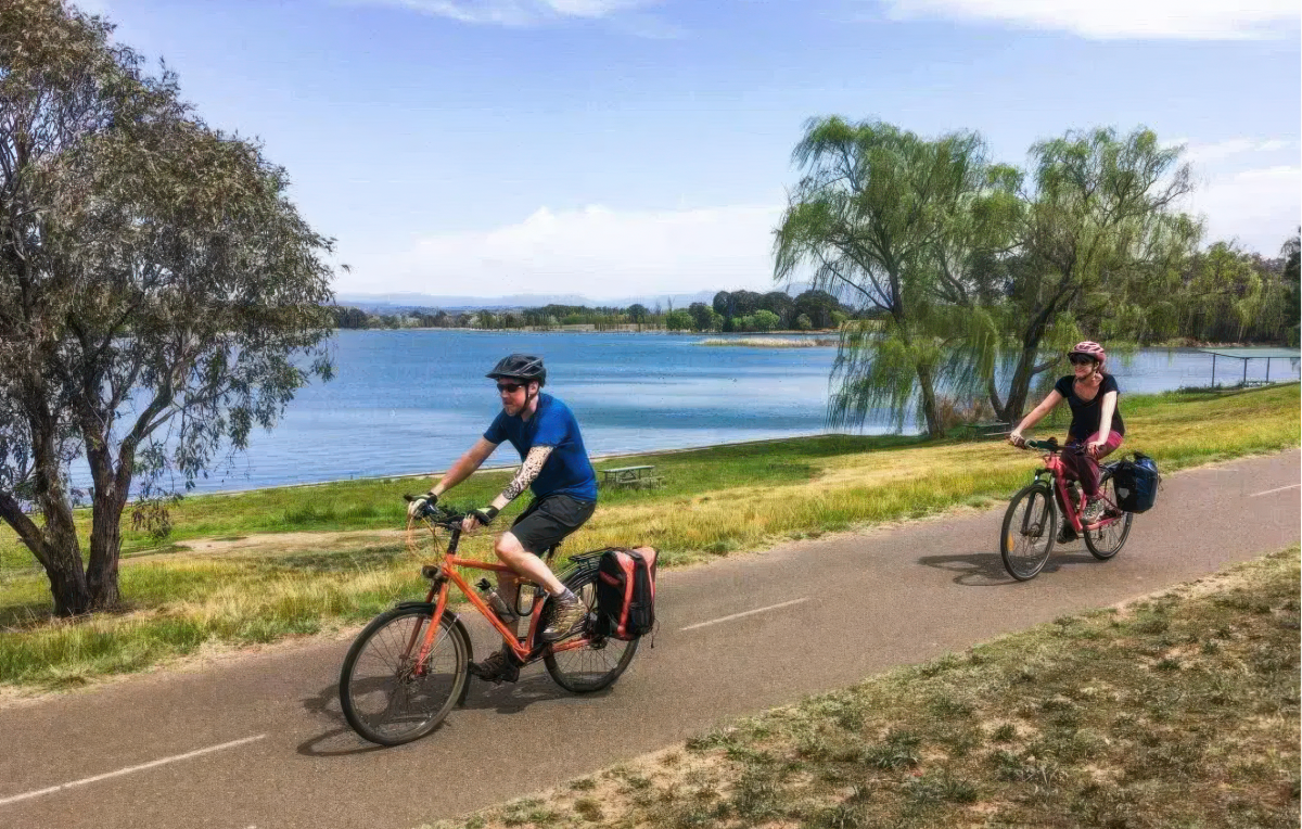 two people riding bikes around a lake