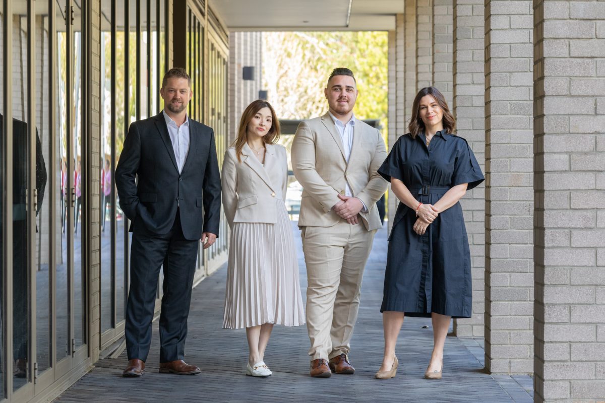 four people standing in an outside walk way