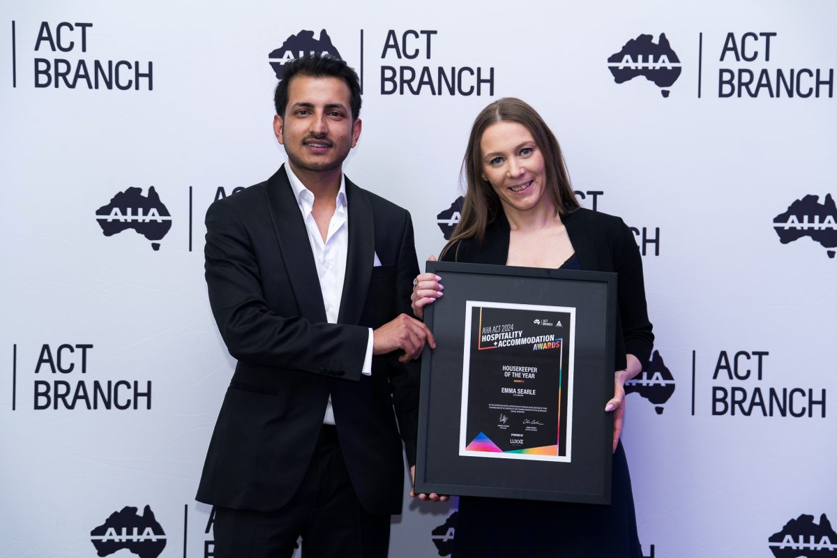 Bivek Poudyal and Canberra QT Hotel's Emma Searle hold plaque