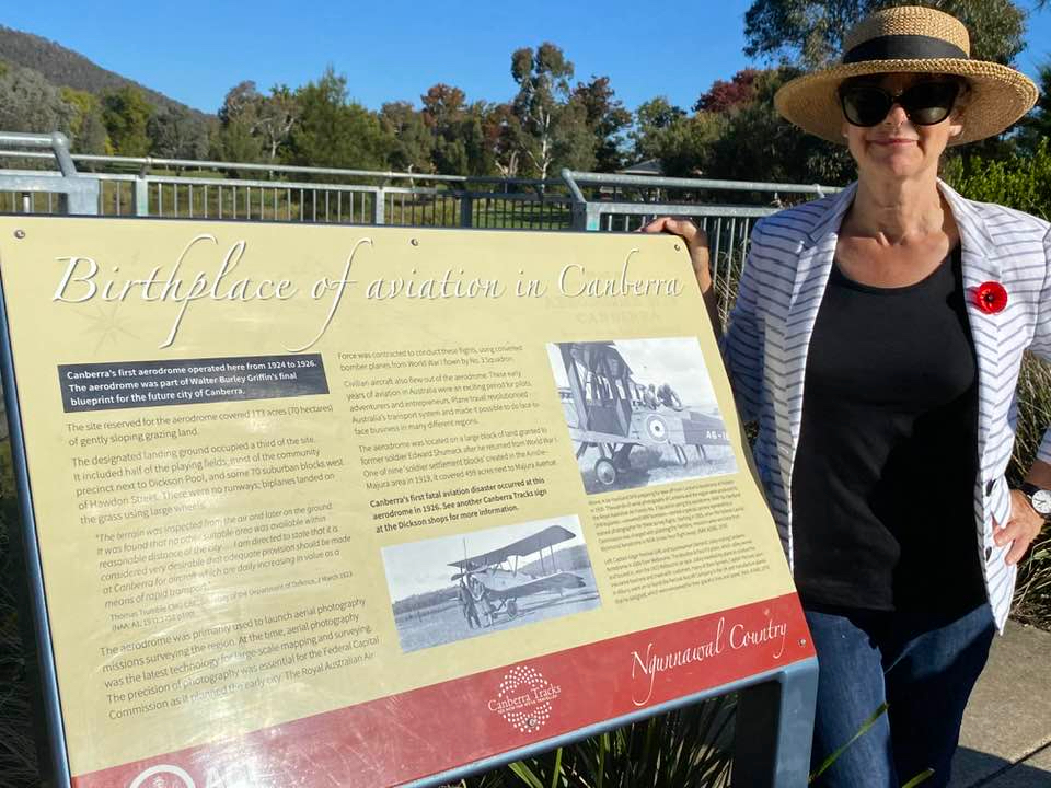 Jane Goffman stands in front of a placard with information about the Dickson aerodrome 