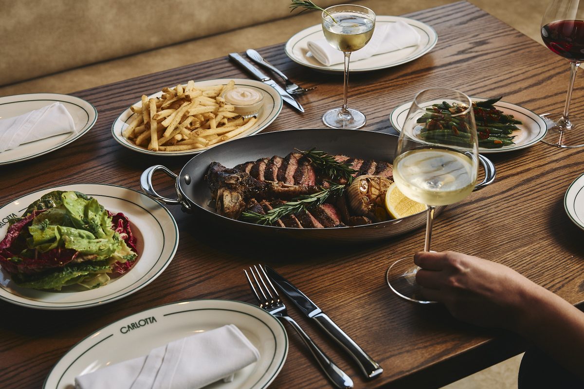 A tray of sliced steak with a side of fries and salad.