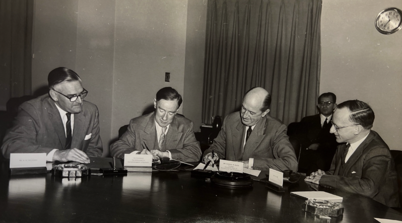 A sepia photograph of four gentlemen writing.